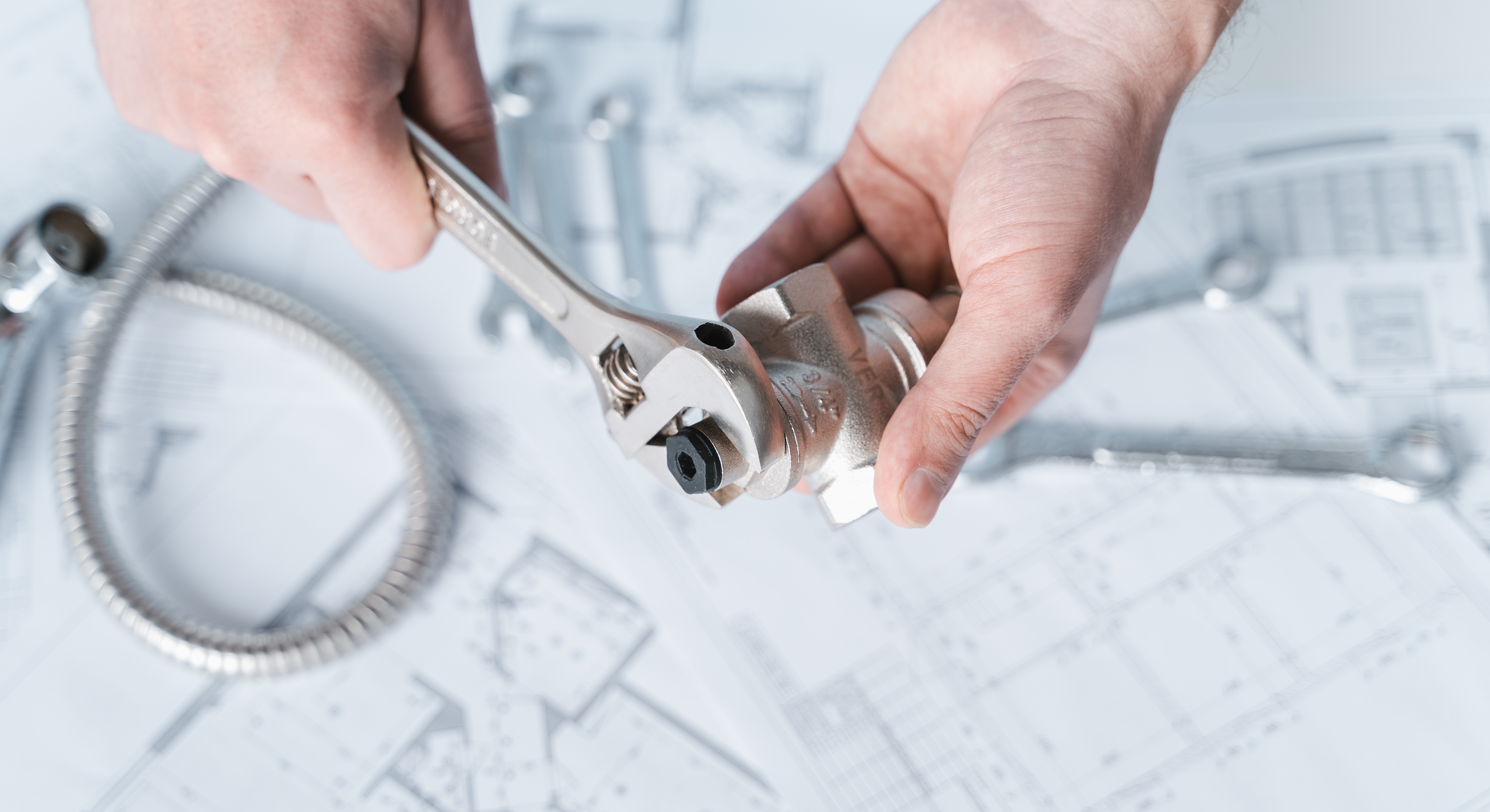 Réparation plomberie avec outils sur plans techniques.