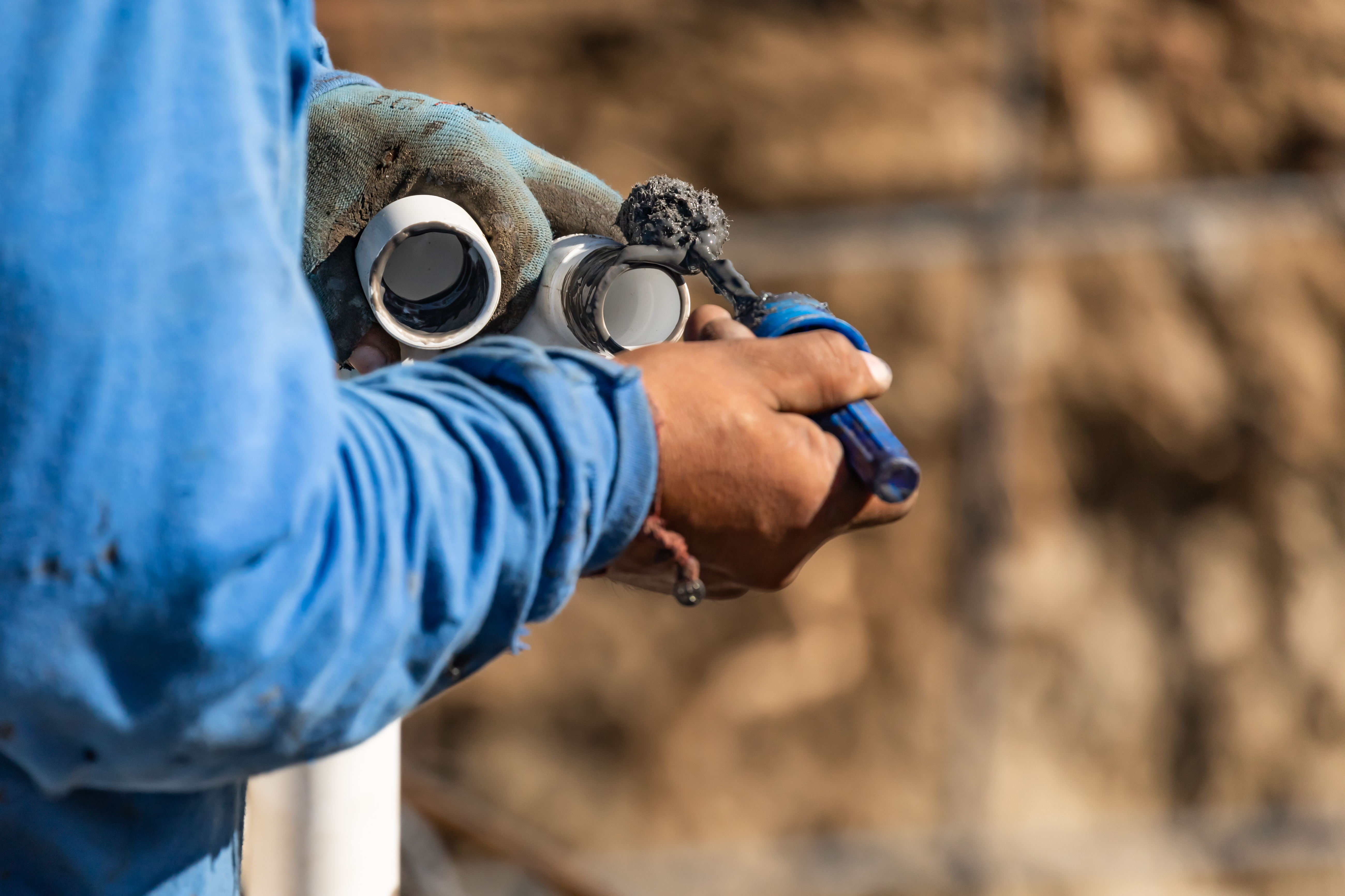 Ouvrier appliquant produit sur tuyaux en chantier