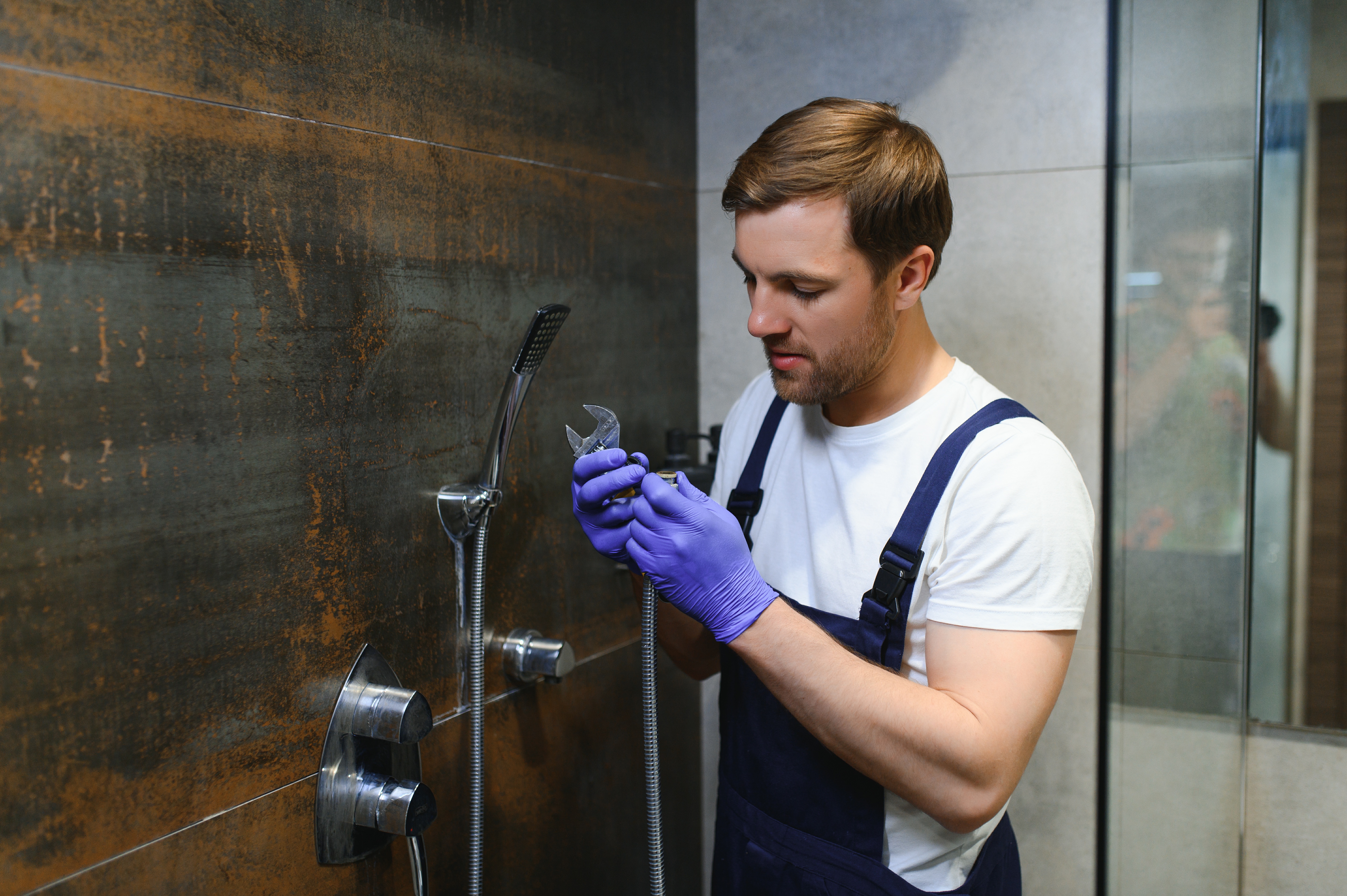 Plombier réparant une douche avec outils