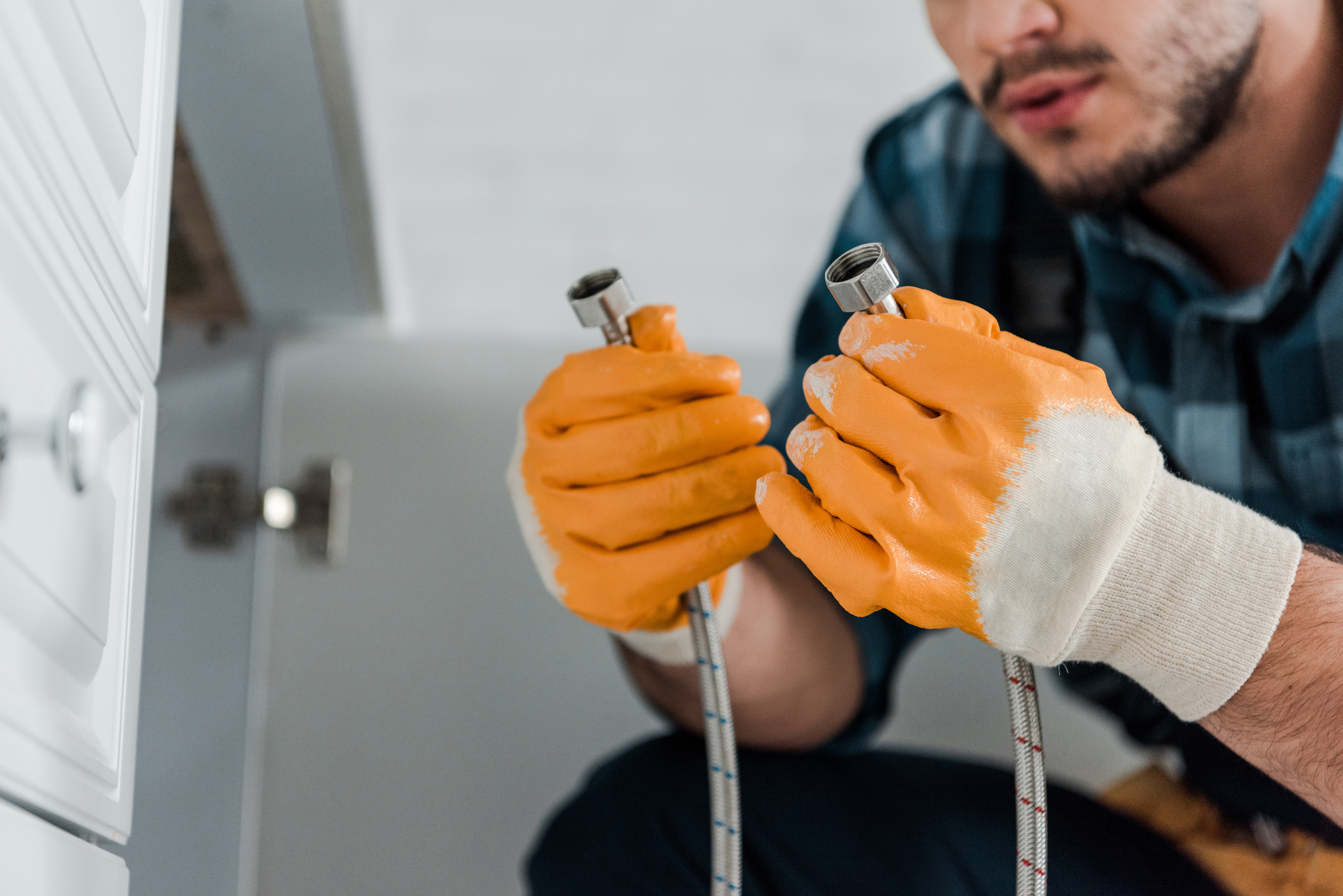 Plombier répare tuyaux avec gants orange