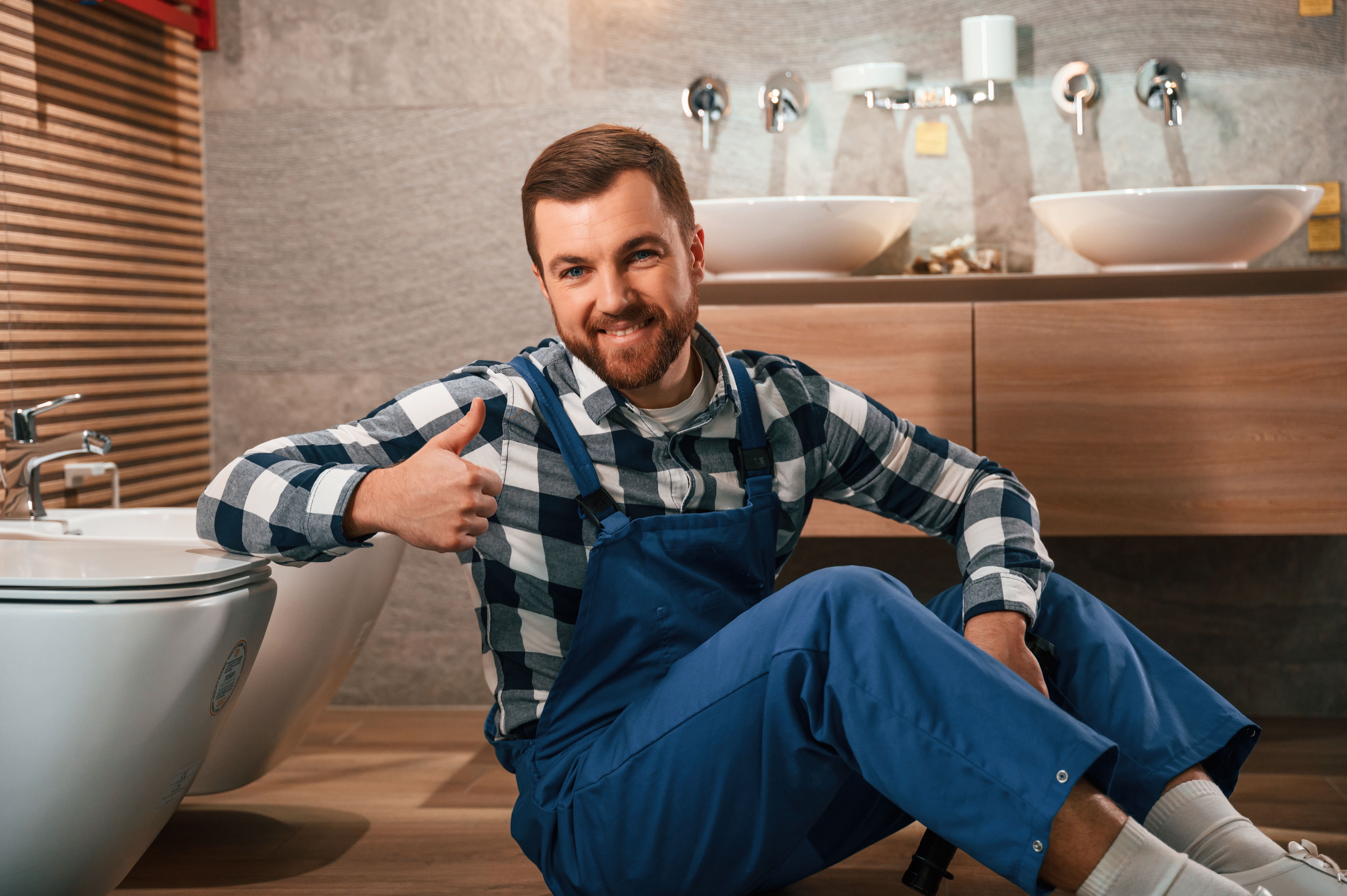 Plombier souriant assis dans une salle de bain.